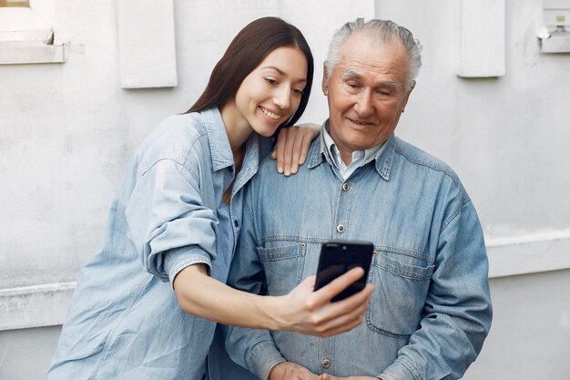 Young woman teaching her grandfather how to use a phone