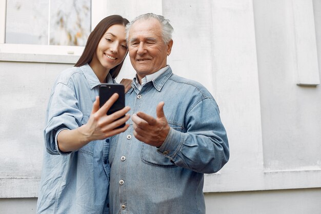 Young woman teaching her grandfather how to use a phone