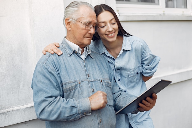 Young woman teaching her grandfather how to use a tablet