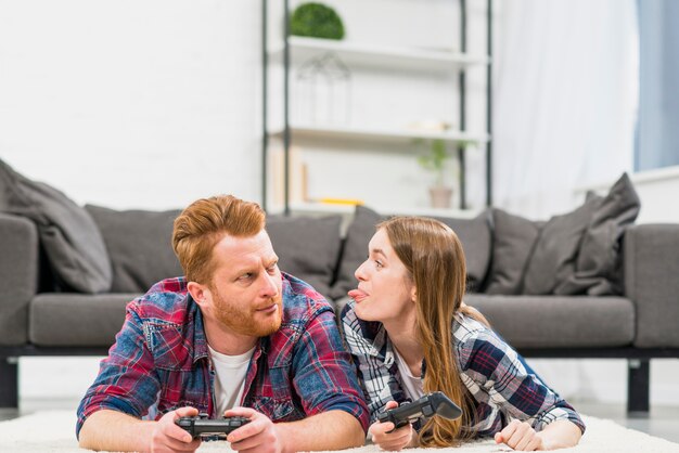 Молодая женщина дразнит своего парня во время игры в видеоигру в гостиной