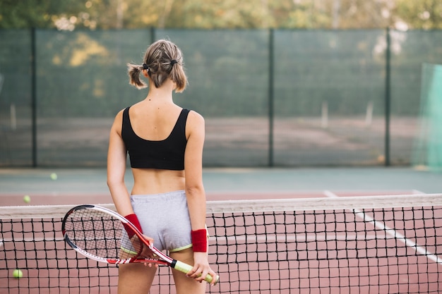 テニスのフィールドで遊ぶ若い女性