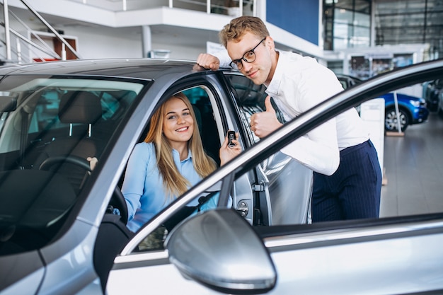 Giovane donna che collauda un'automobile da una sala d'esposizione dell'automobile