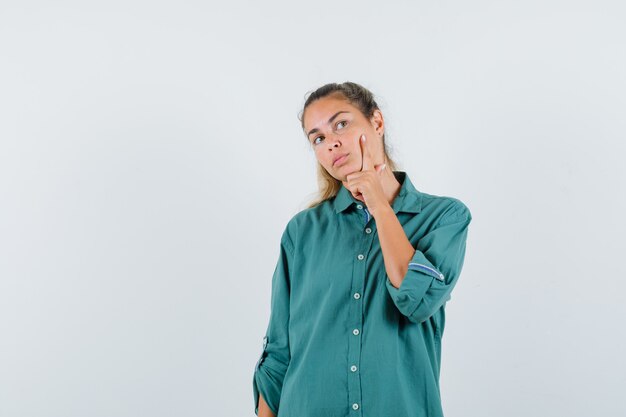 Young woman thinking something in blue shirt and looking pensive