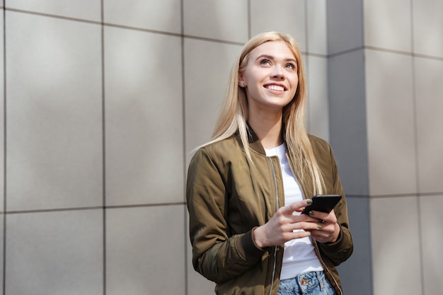 Young woman thinking while using smartphone