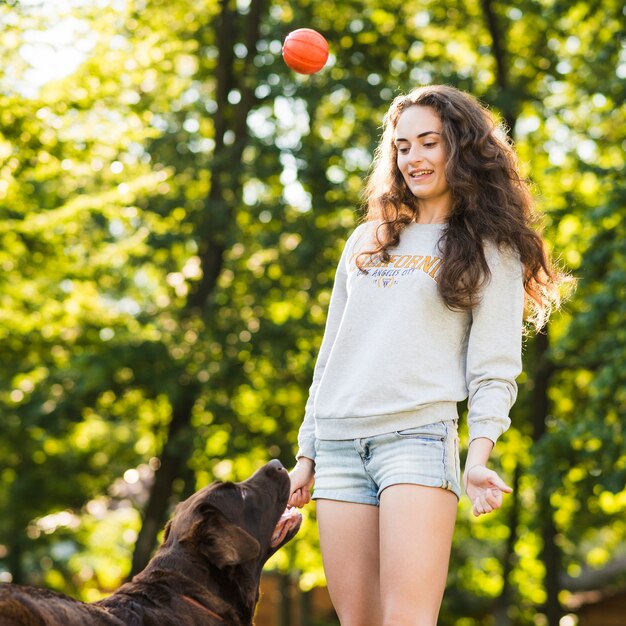 公園で彼女の犬のボールを投げている若い女性