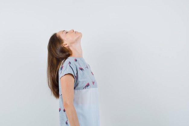 Free photo young woman tilting back her head in t-shirt and looking relaxed. front view.