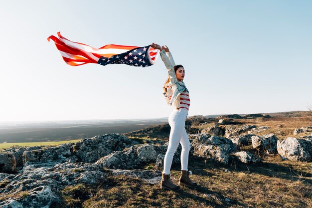 Young woman on top of mountain with American flag fluttering