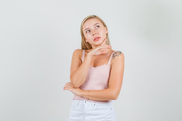 Young woman touching chin with finger while thinking in singlet