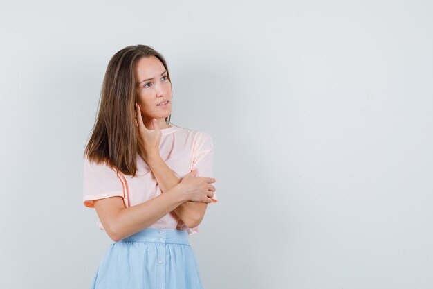 Tシャツ、スカート正面図で彼女の耳に注意深く触れている若い女性。