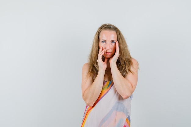 Young woman touching her face skin in summer dress and looking cute. 