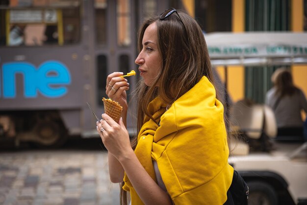A young woman tourist eats ice cream on a city walk