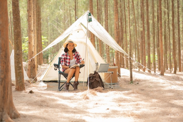 Foto gratuita turista della giovane donna che si siede vicino alla tenda e che legge un libro. concetto di persone e stili di vita. tema di viaggio e avventura. ritratto di turista femminile.