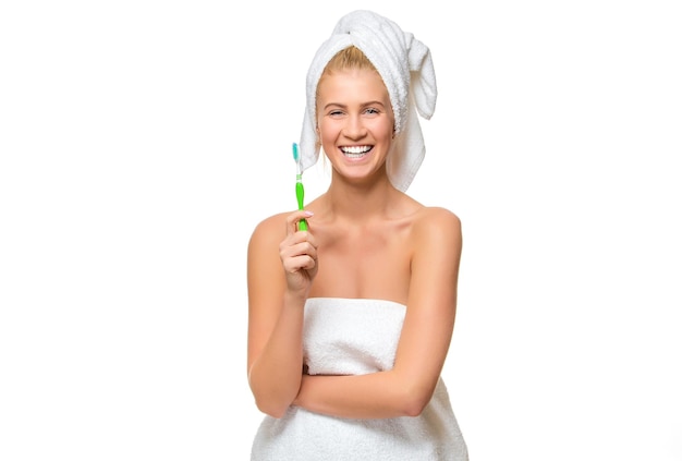 Молодая женщина в полотенце с зубной щеткой улыбается
