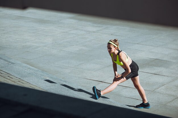 秋の日差しの中で屋外でトレーニングする若い女性。スポーツの概念、健康的なライフスタイル、