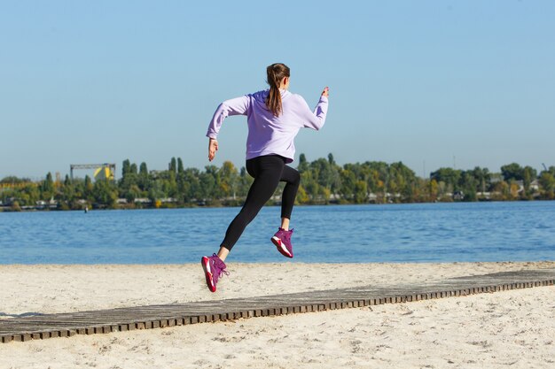 Young woman training outdoors in autumn sunshine. Concept of sport