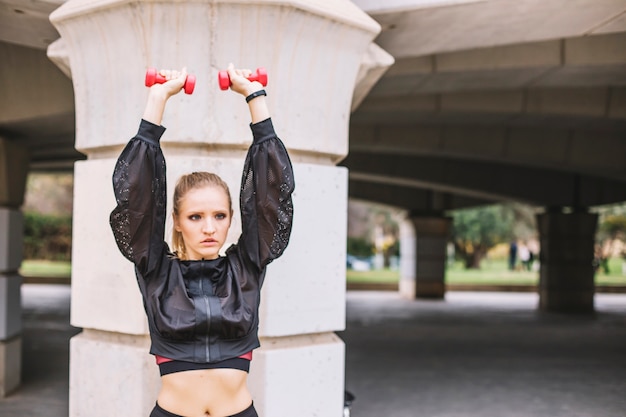 Addestramento della giovane donna con i dumbbells