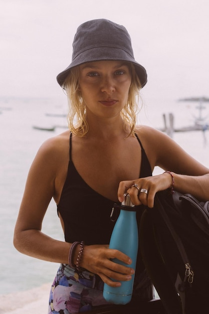 若い女性旅行者は、色付きのボトルから水を飲みます。