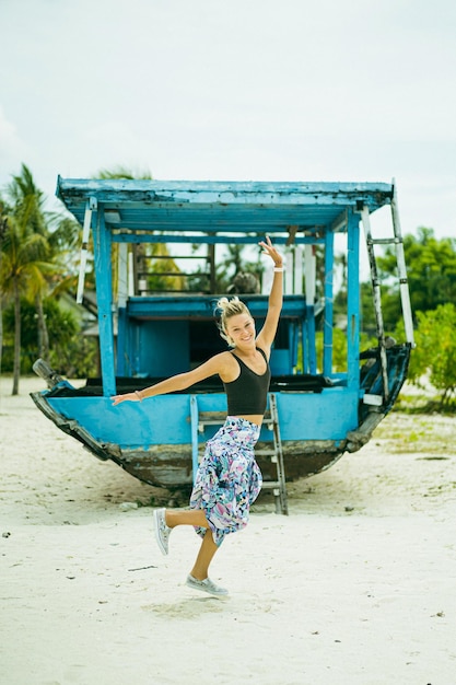 Free photo young woman traveling on the beach against the backdrop of an old ship.