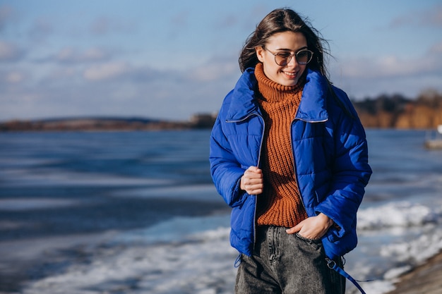 Foto gratuita viaggiatore della giovane donna in giacca blu sulla spiaggia