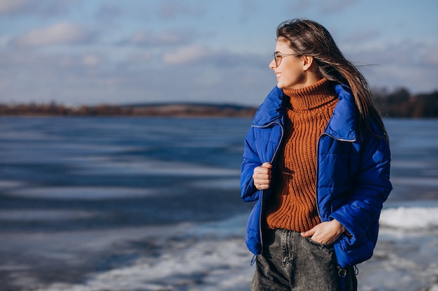 Foto gratuita viaggiatore della giovane donna in giacca blu che guarda il mare