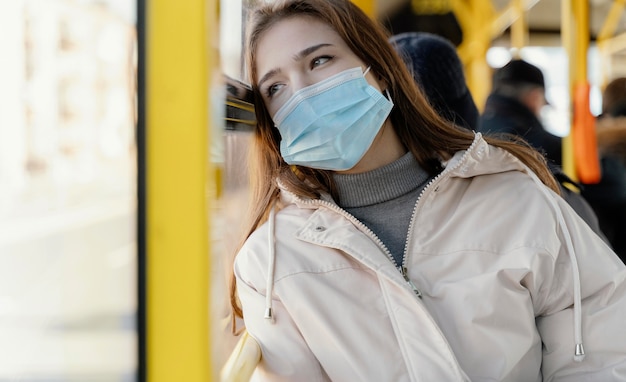 수술 마스크와 시내 버스로 여행하는 젊은 여자