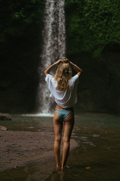 若い女性が滝で写真を撮って島を旅します