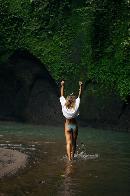 young woman travels around the island taking pictures at a waterfall