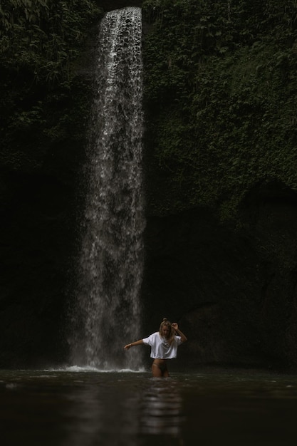 若い女性が滝で写真を撮って島を旅します