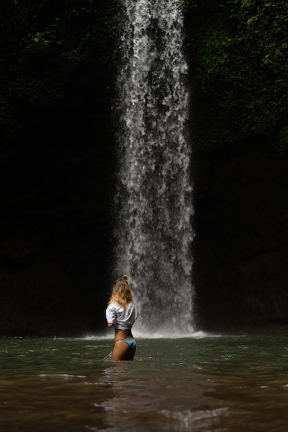 young woman travels around the island taking pictures at a waterfall