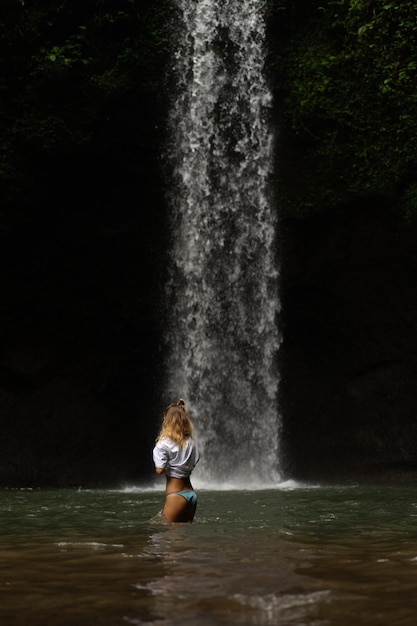 若い女性が滝で写真を撮って島を旅します