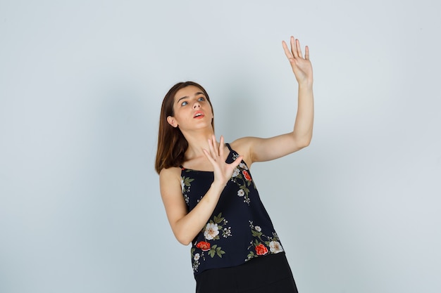 Free photo young woman trying to block herself with hands in blouse, skirt and looking scared. front view.