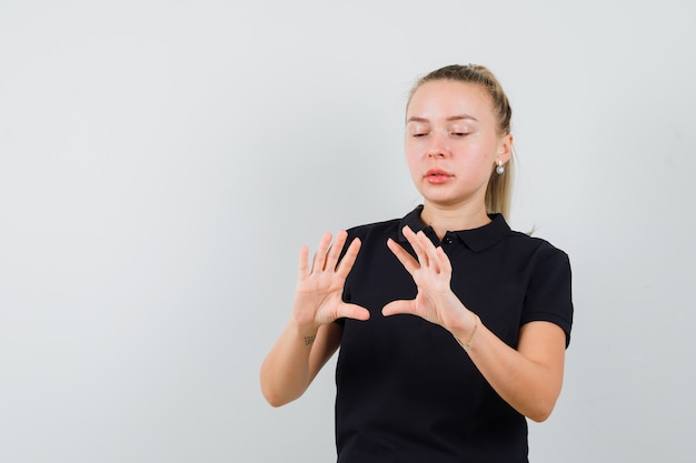 Young woman trying to make triangle shape in striped blouse and looking serious