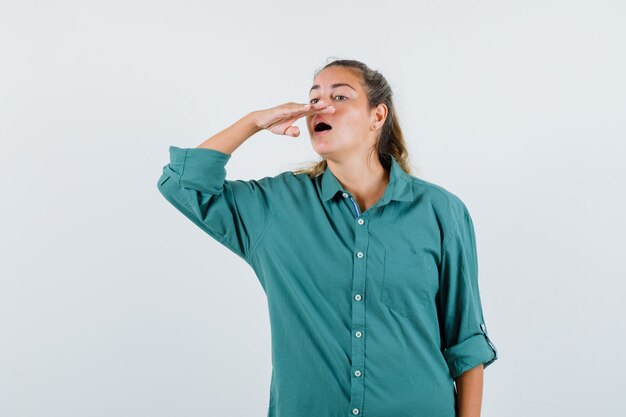 Young woman trying to sneeze in green blouse and looking happy