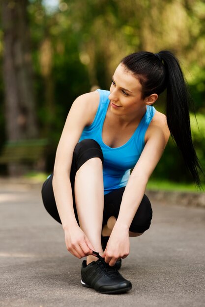 Young woman tying sports shoe