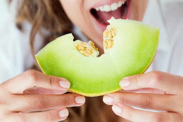 Young woman in underwear eating melon. Isolated on white.