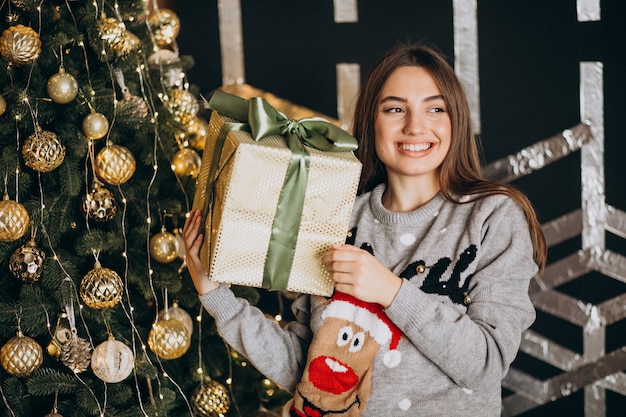 クリスマスツリーでクリスマスプレゼントを開梱する若い女性