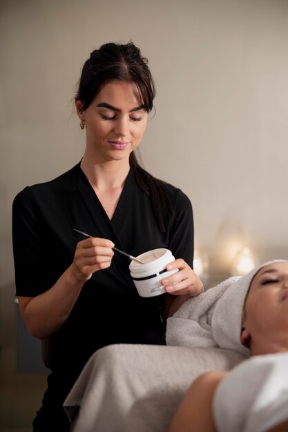 Young woman using a face treatment on her client