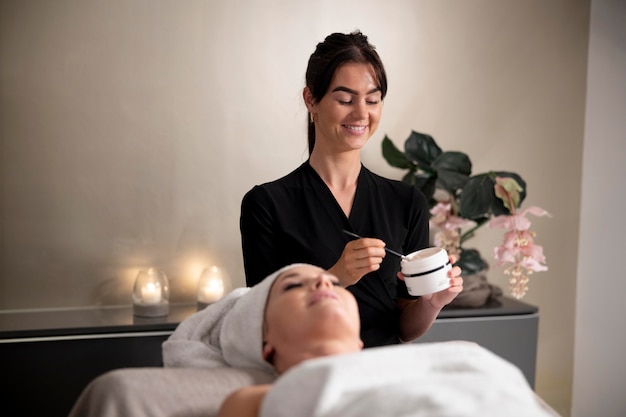 Free photo young woman using a face treatment on her client