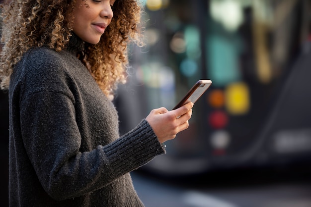 Foto gratuita giovane donna che utilizza il suo smartphone in città