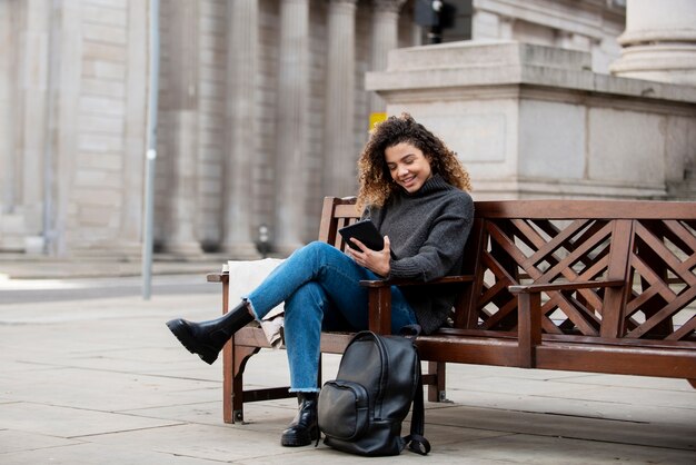 Foto gratuita giovane donna che utilizza il suo smartphone in città