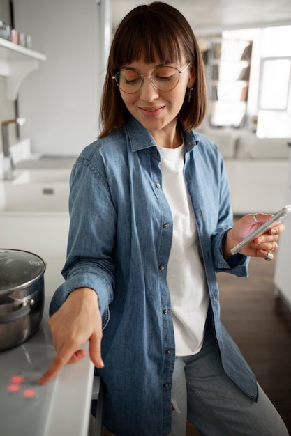 Foto gratuita giovane donna che utilizza la tecnologia domestica