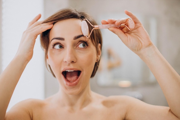 Young woman using jade face roller at home