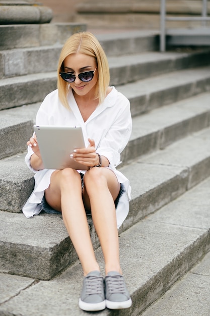 Young woman using laptop computer and smart phone. Beautiful student girl working on laptop outdoor