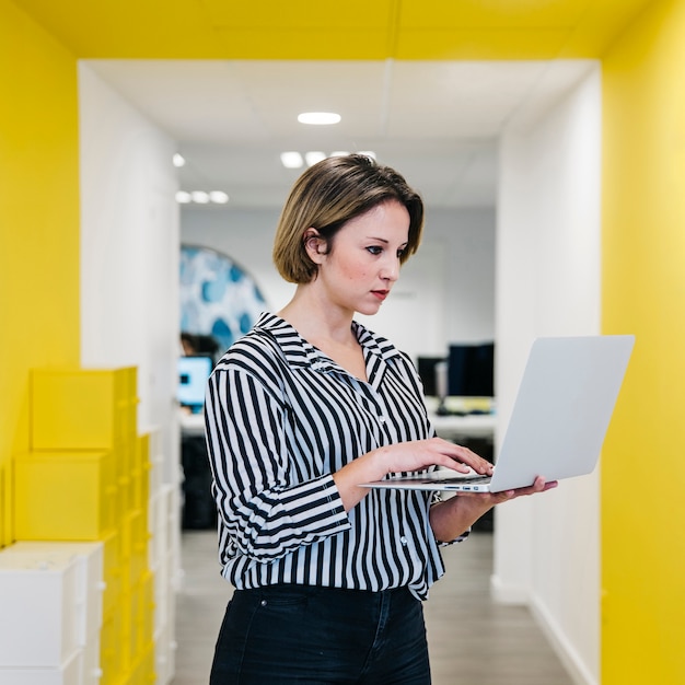 Young woman using laptop in hall of office