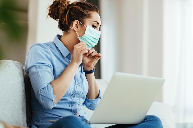 Молодая женщина использует ноутбук и учится онлайн, как правильно носить маску во время эпидемии вируса
