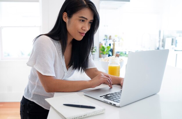 Young woman using laptop and notebook with pen for notes