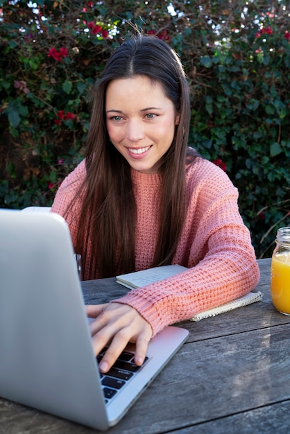 Free photo young woman using laptop outdoors