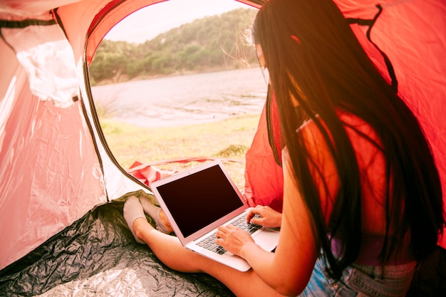 Free photo young woman using laptop in tent