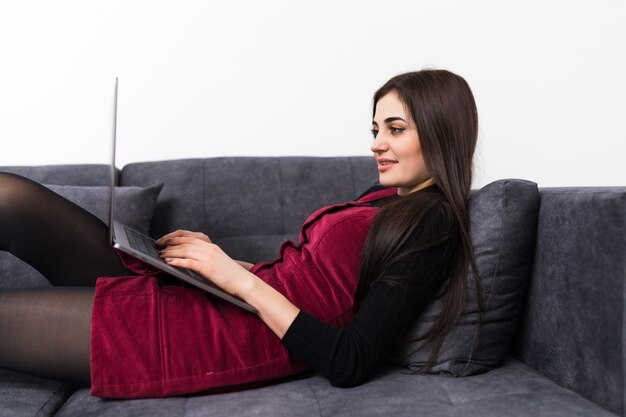 ソファでリラックスしながらラップトップを使用して若い女性