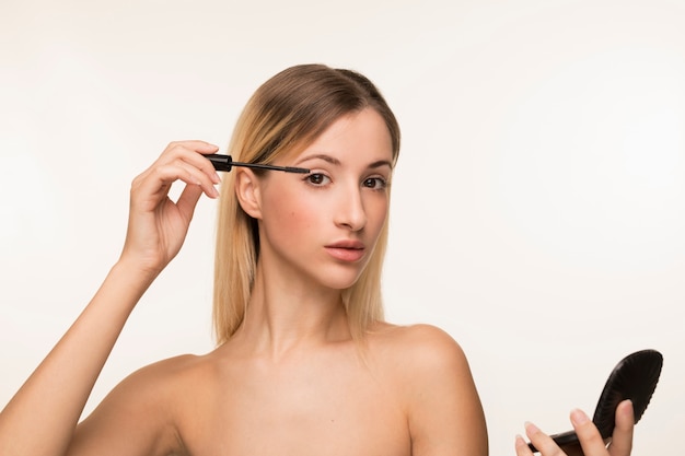 Young woman using mascara 